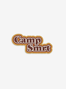 Pictured is a sticker that has the words Camp SMRT in retro brown with a three layered outline of white, orange, and light brown. Perfect to stick on your 4runner or roof tent rack! Available for sale by SMRT Tent in Denver, Colorado, USA.